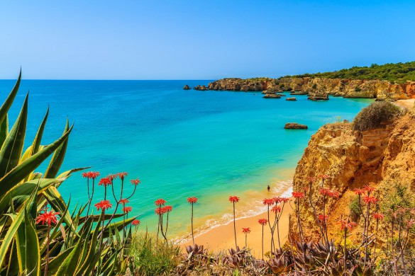 Türkises Meer trifft auf goldgelben Sandstrand und Felswände.