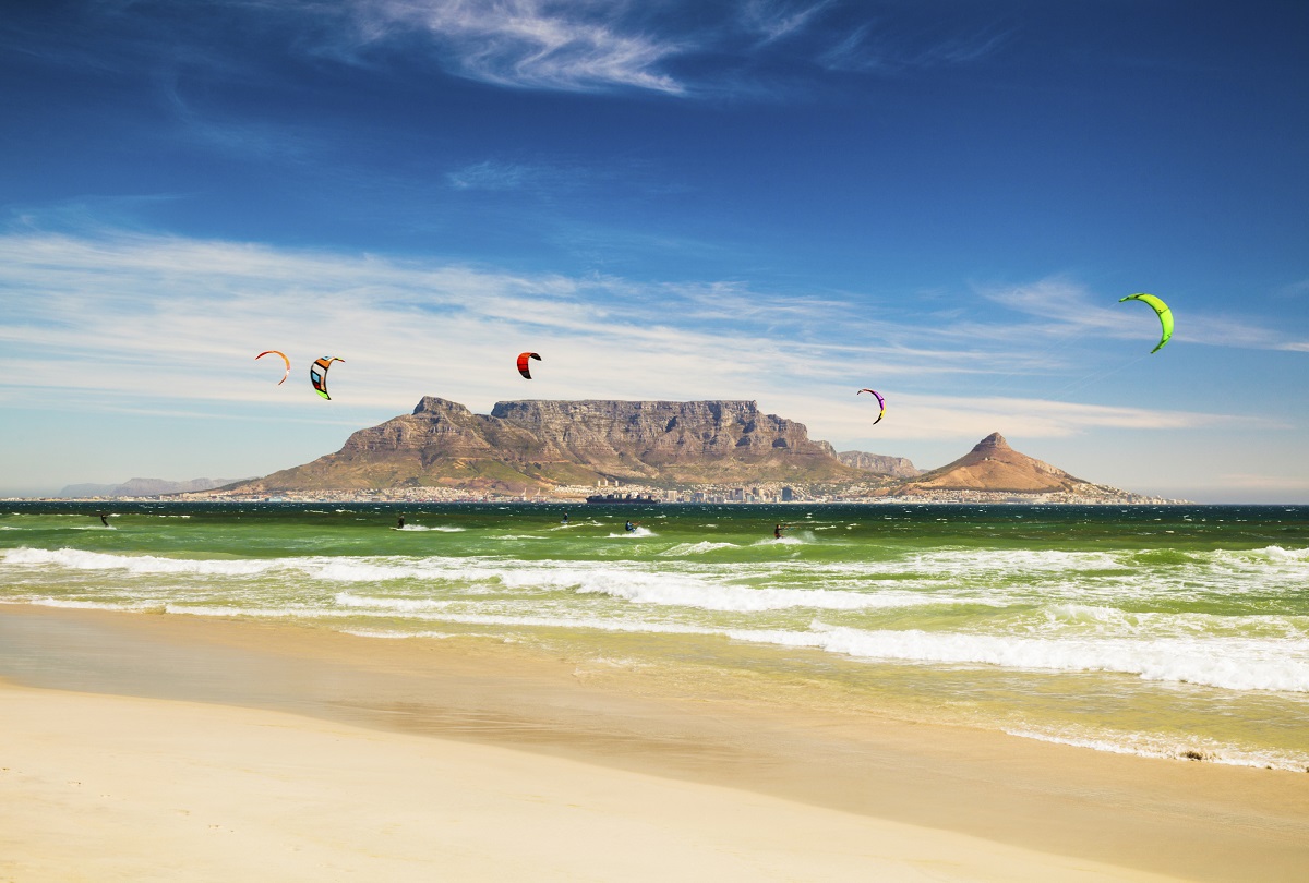 Kite Surfer im grünen Meerwasser vor dem Hintergrund des Tafelbergs.