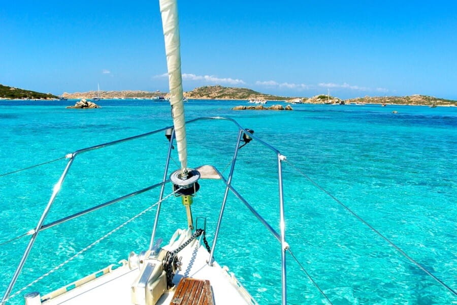 Kristallklares türkisblaues Meer vom Bug eines Segelboots gesehen, ideal für einen Last Minute Urlaub auf Sardinien. Sonniger Tag mit leichtem Wellengang.