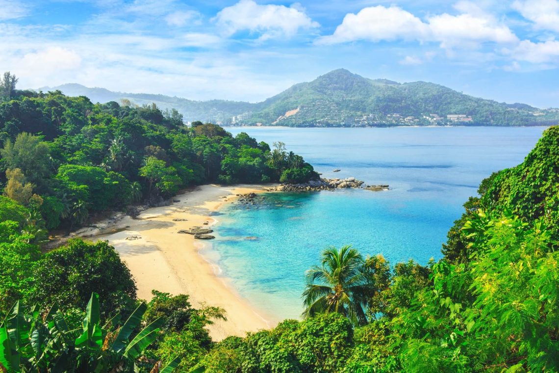 Idyllisches Panorama einer geschwungenen Bucht in Thailand, umgeben von üppigem Grün und einem türkisblauen Meer, ermöglicht einen entspannten Urlaub am Meer.