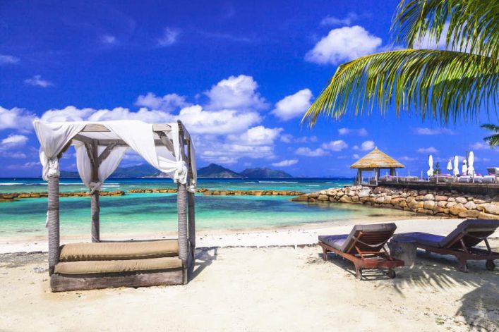 Einladender Strand mit türkisem Wasser, weißen Sand und einer Luxus-Liege, umgeben von Top 10 der schönsten Strände.